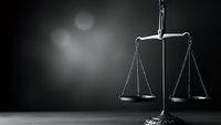 Scales of justice on dark background with dramatic lighting for legal concepts, law firm branding, courthouse presentations and judicial system materials.