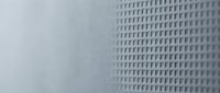 Minimalist architectural detail showing geometric grid pattern on modern building facade with soft natural lighting and neutral tones.