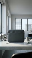 Modern minimalist workspace with black laptop sleeve on wooden desk in bright office interior with natural light and urban view.