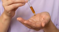 Healthcare professional dispensing liquid medicine from dropper into palm for precise dosage measurement and administration.