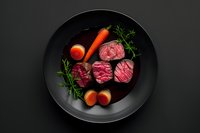 Sliced medium rare beef tenderloin steak on black plate with fresh carrots, cherry tomatoes and rosemary sprigs against dark background, food photography.