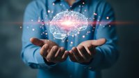 Professional man in blue shirt holding glowing digital brain hologram with neural network connections representing artificial intelligence and innovation.