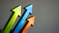 Colorful upward pointing arrows in green blue and orange showing growth progress and success on gray background for business presentations.