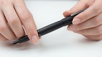 Hands holding black stylus pen on white background, digital drawing tool for tablets and touchscreen devices, technology accessory for artists.