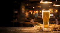 Golden beer glass with wheat stalks on wooden table in warm pub atmosphere with bokeh lights creating cozy evening ambiance for hospitality marketing.
