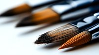 Artistic paintbrushes with natural bristles in macro view showing fine details and textures against blurred background, highlighting craftsmanship and creative tools.