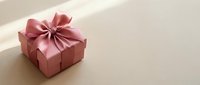 Pink gift box with elegant satin ribbon bow on neutral beige background, perfect for celebrations, holidays, birthdays, and special occasions.