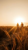 Romantic couple holding hands walking through golden wheat field at sunset with warm sunlight rays creating dreamy atmosphere for love and relationship concepts.