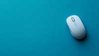White wireless computer mouse on turquoise blue background with copy space, minimalist office technology concept for business and remote work.