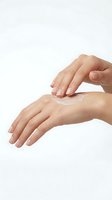 Woman applying moisturizing cream to hand against white background. Skincare routine, cosmetics, lotion application, beauty treatment, dermatology, hand care product demonstration.
