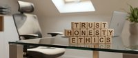 Modern office desk with wooden letter blocks spelling trust honesty ethics representing corporate values and business integrity in professional workspace.