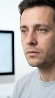 Thoughtful middle-aged Caucasian man in gray shirt looking away contemplatively in modern office setting with natural lighting for professional content.