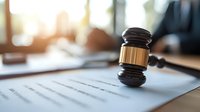 Wooden judge gavel on legal document in attorney office with morning sunlight, law firm workplace background showing justice and legislation concept.