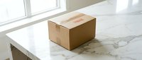 Cardboard delivery package box on white marble table near window with natural light for shipping and e-commerce business concepts.