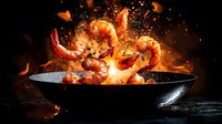 Fresh prawns tossed with spices in black pan against dark background with fire flames and motion effect creating dramatic culinary scene.
