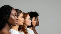 Diverse group of young women in profile showing multicultural beauty and unity in white tops against neutral background for inclusive campaigns.