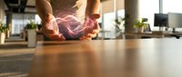 Hands holding glowing digital brain with neural networks in modern office workspace representing artificial intelligence and innovation technology.