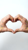 Hands covered in colorful paint splatter forming a heart shape on white background, symbolizing love for art and creativity.