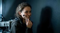 Young mixed-race woman talking on smartphone with genuine smile in modern office environment, professional communication and business networking.