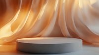 Round gray podium against flowing orange and white silk fabric background creates dramatic product display space with soft lighting and elegant shadows.
