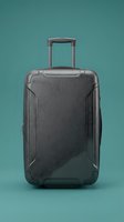 Gray hard-shell rolling suitcase with extended handle on teal background, front view. Modern travel luggage for vacation and business trips.