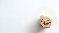 Wooden stamp with handshake icon on white background for business partnership and agreement concepts in corporate branding materials.