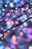 Glowing fairy lights on dark branches create magical bokeh effect in blue, pink and purple tones, capturing dreamy holiday atmosphere for festive designs.