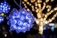 Glowing blue LED cluster light decoration against blurred golden bokeh background creates magical holiday atmosphere for festive seasonal displays.
