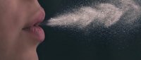Person exhaling visible breath in cold air creating misty cloud against dark background for winter health and respiratory concepts.