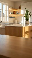 Modern kitchen interior with wooden island, white countertops, and warm lighting. Features open shelving, potted plant, and natural sunlight from window for home design projects.