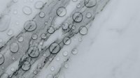 Water droplets on transparent glass surface creating abstract pattern with circular shapes and reflections for modern design projects.