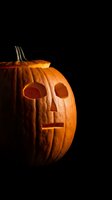 Carved pumpkin jack-o-lantern with glowing face on black background for Halloween decorations and seasonal celebrations.