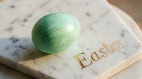 Green speckled Easter egg resting on a marble board with gold Easter lettering, soft natural light, spring holiday celebration concept.