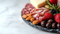 Gourmet charcuterie board with salami, cheese, fresh strawberries, almonds and olives on slate platter for entertaining and appetizer presentation.
