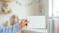 Woman holding blank white card in nursery room with pastel decorations, toys and soft furnishings, suitable for greeting cards, announcements and baby product marketing.