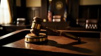Wooden judge gavel on desk in courtroom with warm lighting. Legal justice symbol for law firm presentations, legal services marketing materials.