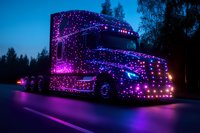 Semi truck decorated with purple and blue LED lights driving on highway at dusk creating spectacular light display for transportation and logistics industry.