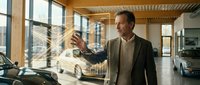 Middle-aged Caucasian businessman examining luxury car in modern showroom with large windows and wooden ceiling beams for automotive sales presentation.