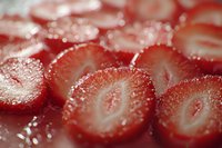 Fresh sliced strawberries with natural sugar crystals showing detailed texture and vibrant red color in macro photography, suitable for food industry and culinary design.