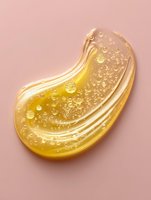 Golden honey or syrup drop with bubbles on pink background, glossy texture and flowing liquid effect creates luxurious cosmetic product visual appeal.