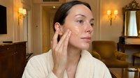 Young woman applying skincare cream to face in luxury hotel room during morning beauty routine for anti-aging treatment and healthy glowing skin care.