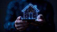 Glowing blue hologram house floating above hands in dark background, digital real estate concept showing smart home technology and property innovation.