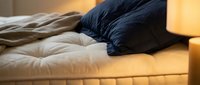 Cozy bedroom scene with layered pillows and soft bedding illuminated by warm candlelight, perfect for home decor, lifestyle, and relaxation content.