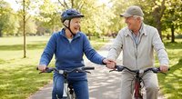 Happy senior couple enjoying bicycle ride together in sunny park, active lifestyle and healthy aging concept for retirement wellness.