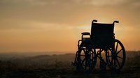 Empty wheelchair silhouetted against golden sunset sky over rural landscape, symbolizing disability awareness, accessibility, hope, and inclusion in healthcare and social support contexts.
