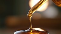 Golden liquid drops falling from dropper creating ripple effect on smooth surface with warm ambient lighting and bokeh background for wellness concept.
