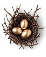 Golden eggs nestled in brown twig nest against white background, symbolizing wealth, investment and financial growth concept. Isolated object for design use.