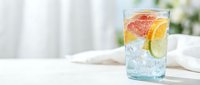 Refreshing citrus infused water with grapefruit and lime slices in glass on white table. Healthy detox drink for summer hydration and wellness lifestyle.