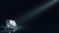 Sparkling diamond gemstone on dark surface with dramatic lighting and copy space for luxury jewelry and precious stone concepts.