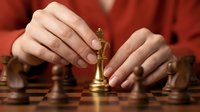 Woman in red placing golden king chess piece on wooden board, symbolizing strategy, leadership, and winning business decisions.